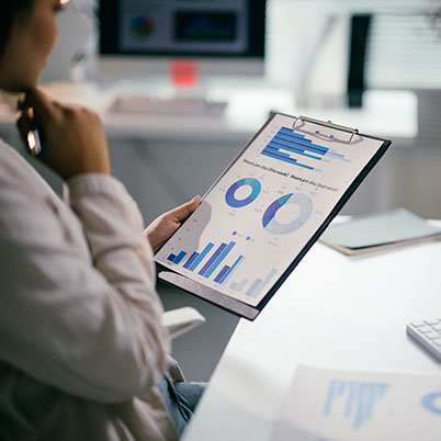 Businesswoman reviewing financial data, using charts and graphs for analysis and strategic decision-making in a modern office setting