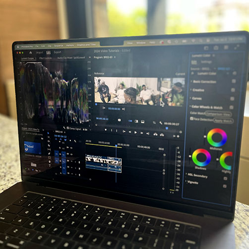 Image of laptop in front of window with Lumetri Color Panel in Premiere pro on screen.