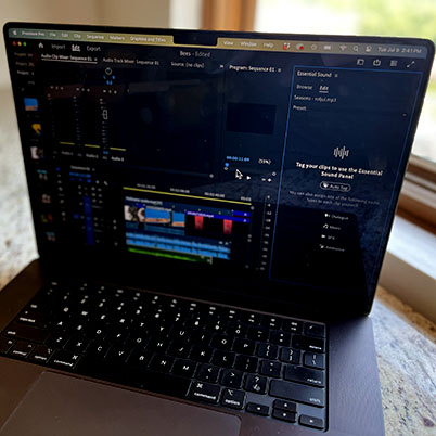 Image of Macbook Pro on quart countertop in front of window with focus on Audio panel in Premiere